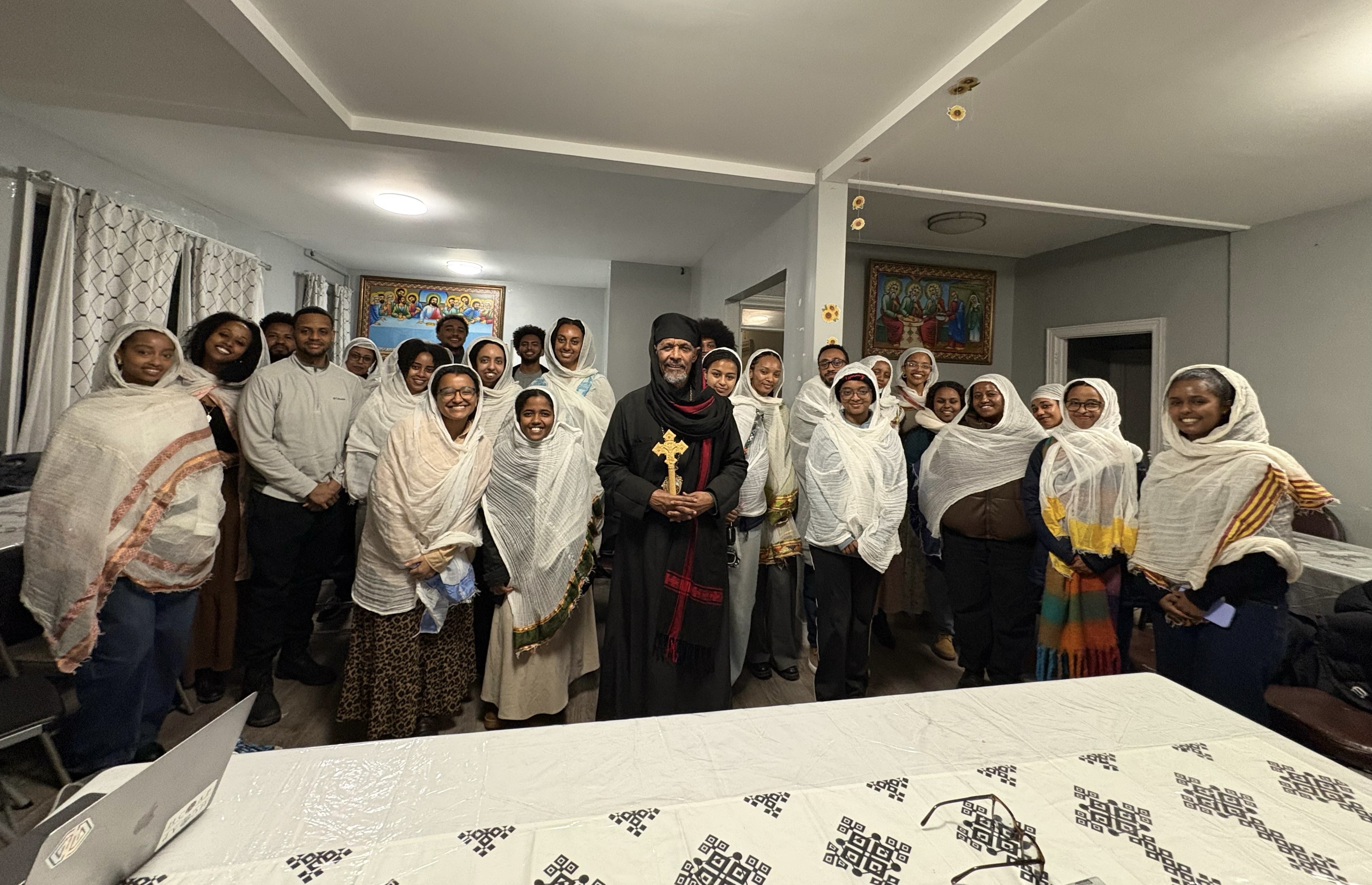 Abune Petros poses with a large group of OTY NYC members after a community gathering